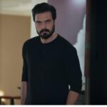 Kadr pokazuje Yamana stojącego przed uchylonymi drzwiami pokoju.