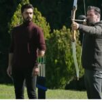 Kadr ukazuje Fikreta i Yamana w ogrodzie. Fikret trzyma w rękach łuk, napiął cięciwę, gotowy do strzału.