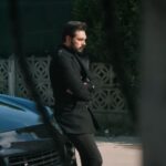 Yaman wytrwale czeka przed domem Fikreta, opierając się o maskę swojego samochodu.