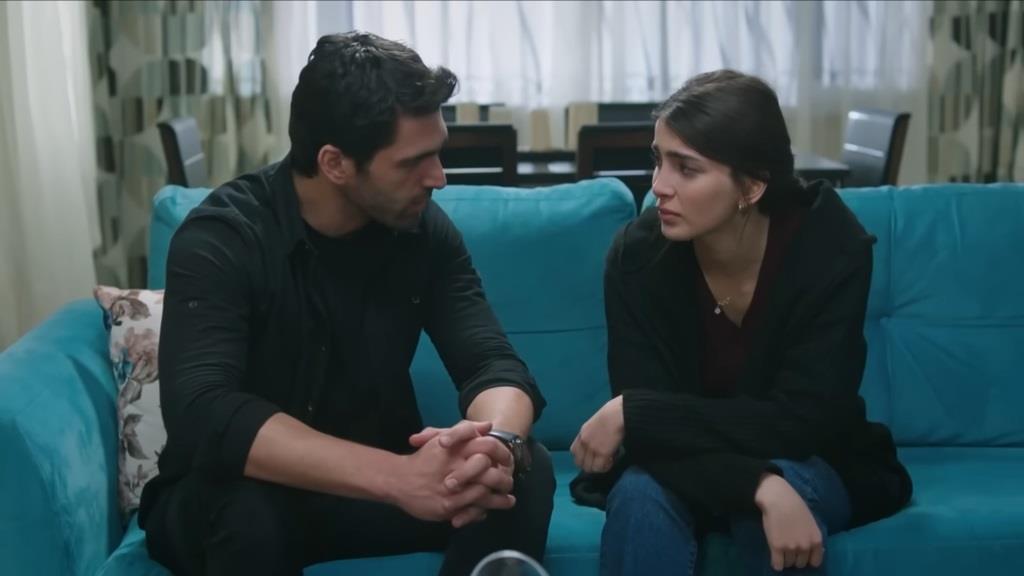 Ali i Duygu siedzą na sofie. Na twarzy Duygu maluje się poczucie winy.