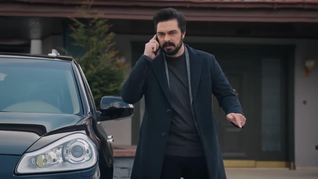Yaman rozmawia przez telefon obok samochodu.
