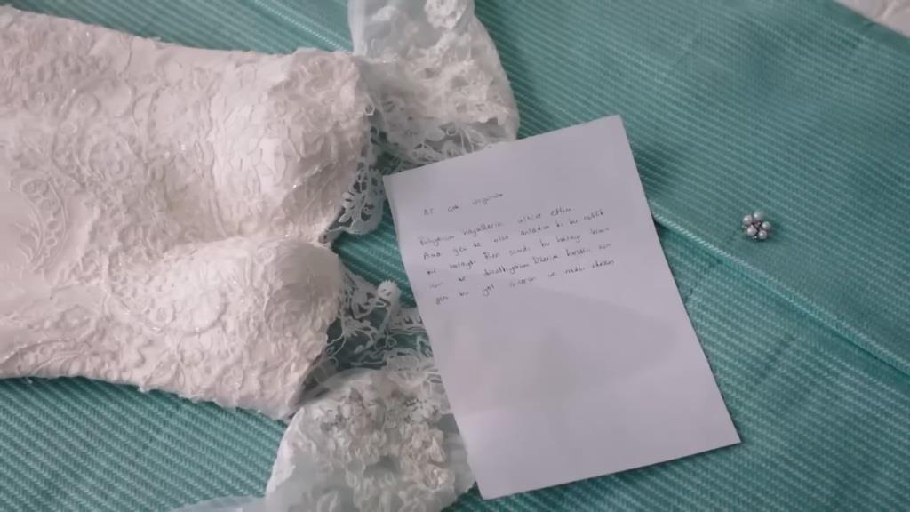 Zbliżenie na zostawione przez Duygu suknię ślubną oraz list.