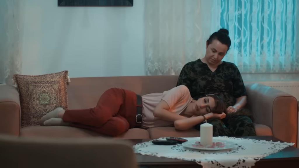 Duygu leży na kanapie, trzymając głowę na nogach matki.