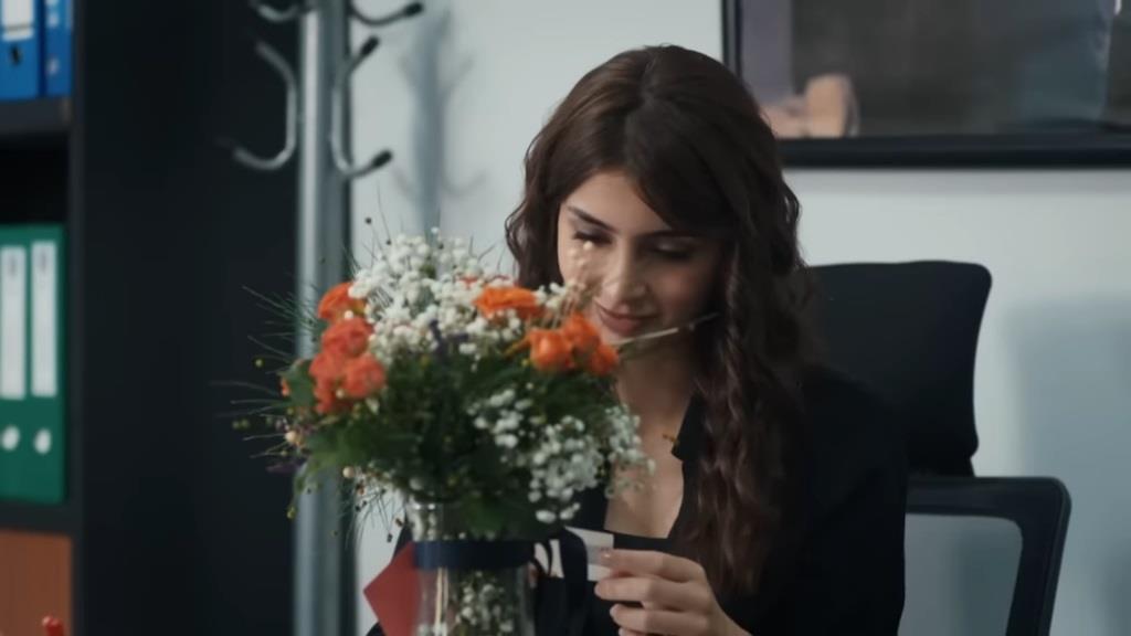 Duygu wpatruje się w bukiet kwiatów.