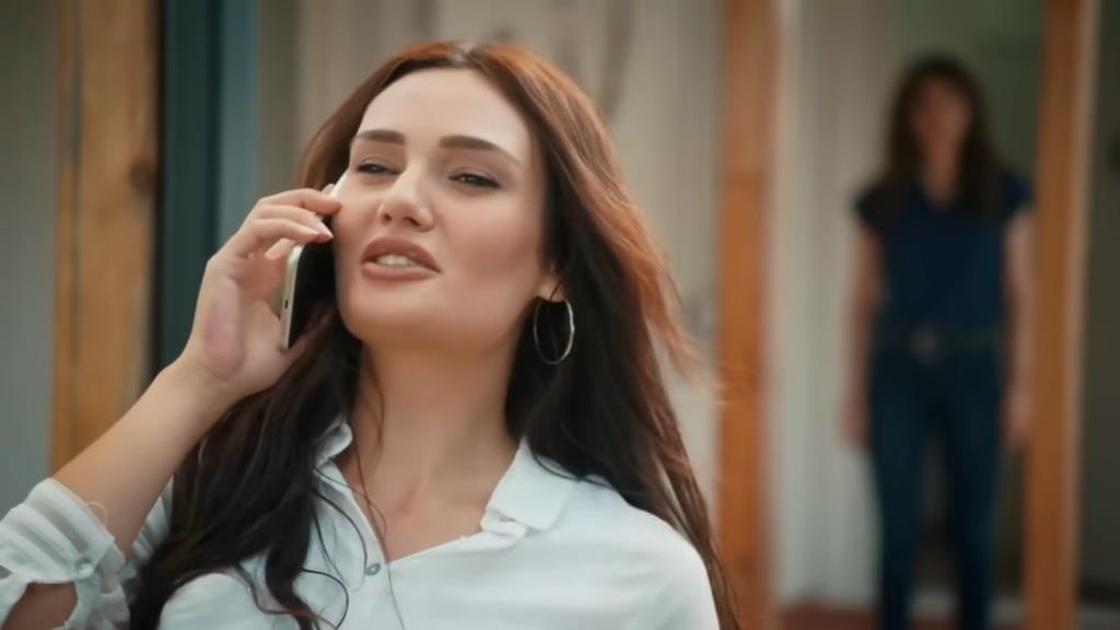 Yagmur rozmawia przez telefon. Na drugim tle widać rozmazaną sylwetkę Duygu.