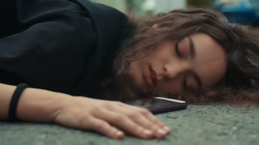 Nana leży na drodze. Obok jej głowy leży rozbity telefon.