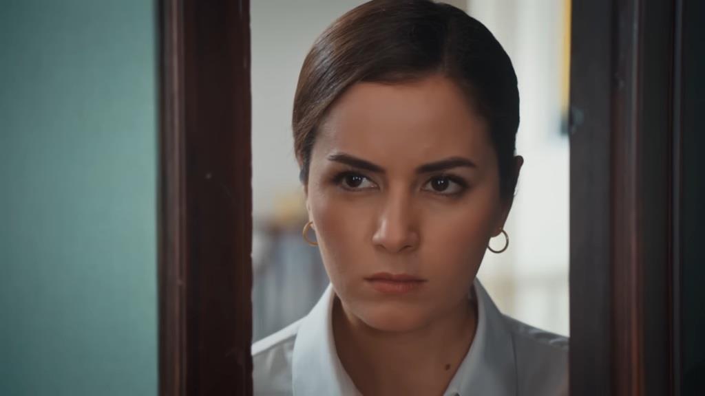 Aynur zagląda do pokoju Nany przez uchylone drzwi. Jej twarz ma napięty, gniewny wyraz.