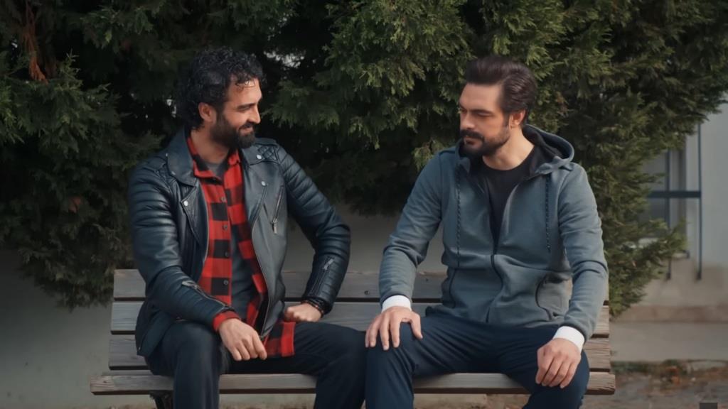 Ferit i Yaman rozmawiają, siedząc na ławce.