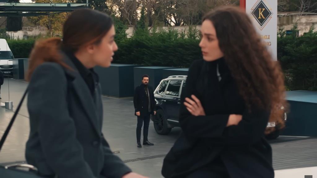 Pinar i Nana rozmawiają na parkingu przed firmą. Stojący przy swoim samochodzie Yaman obserwuje je.