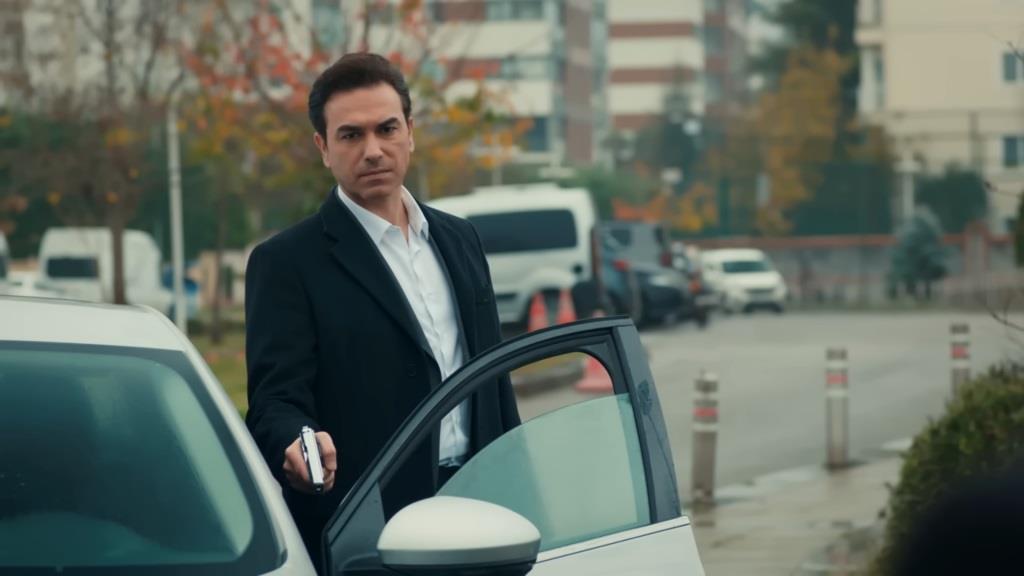 Nedim wysiada z auta, trzymając w ręku pistolet.