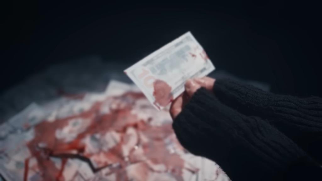 Nana trzyma zakrwawiony banknot w rękach - scena z jej koszmaru.