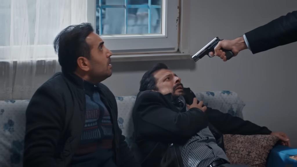 Nedim celuje do Idrisa. Obok Idrisa siedzi Kazim.
