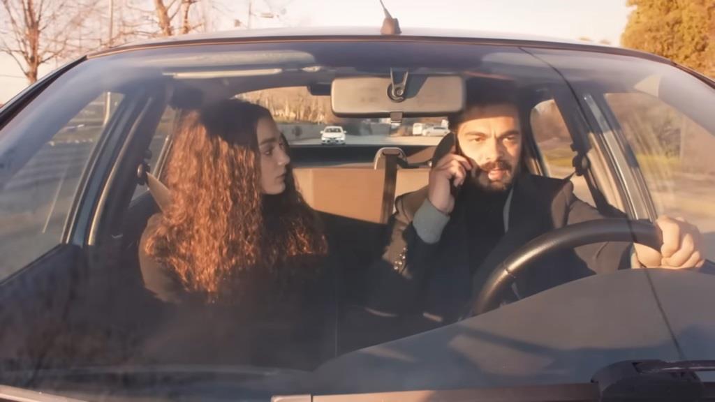 Nana i Yaman w samochodzie. Mężczyzna w napięciu rozmawia przez telefon.