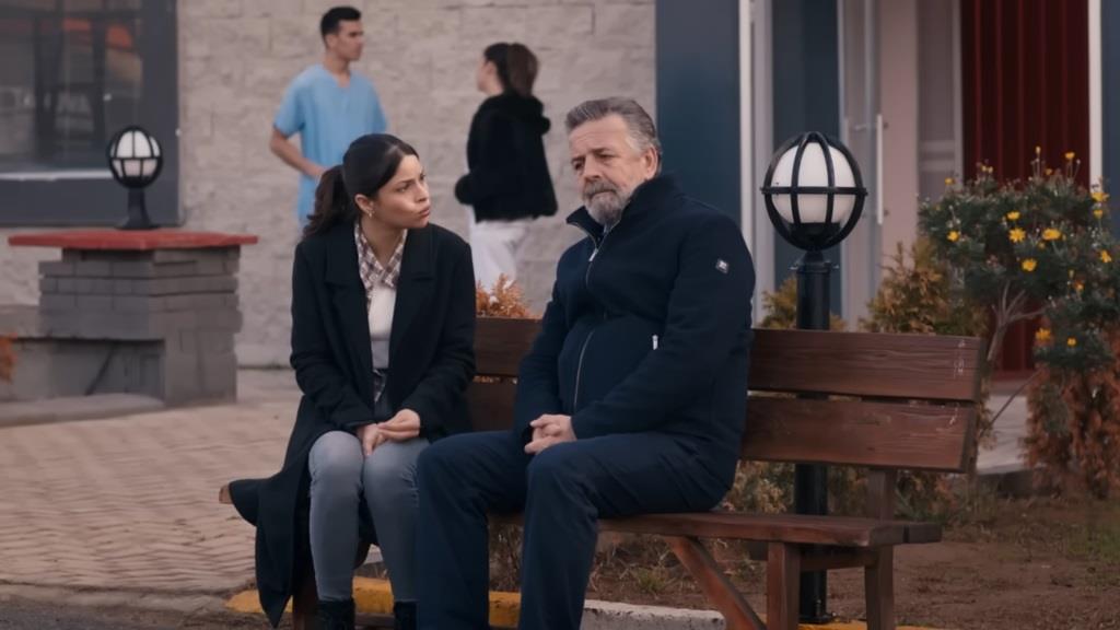 Ayse i jej tata siedzą na ławce przed szpitalem.