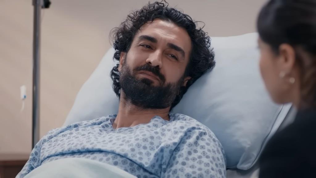Ferit leży na szpitalnym łóżku. Z uśmiechem patrzy na twarz żony.