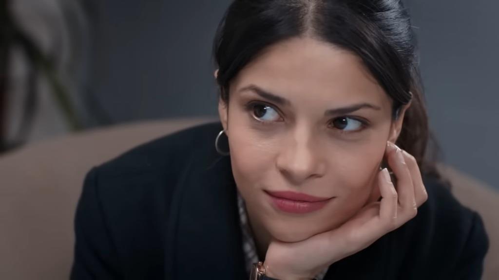 Ayse opiera brodę na dłoni, z uśmiechem spoglądając na Ferita