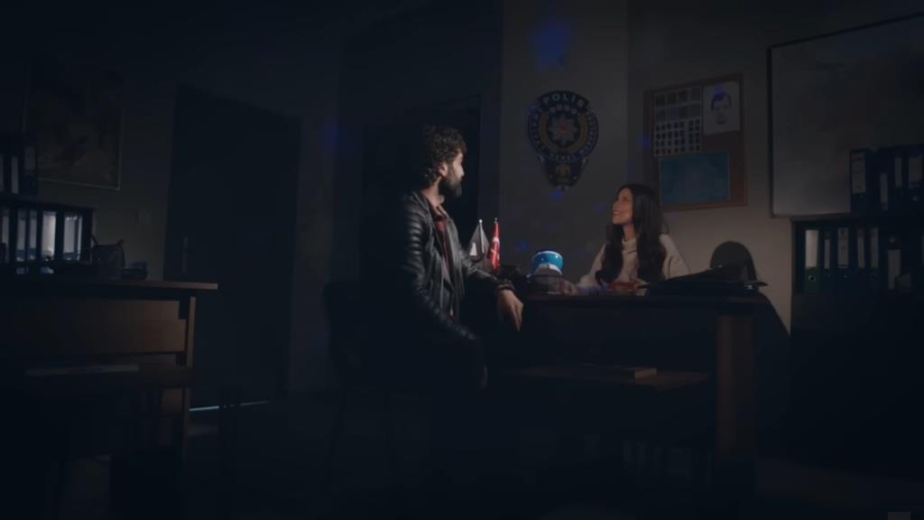 Ferit i Ayse przyglądają się gwiazdom wyświetlanym przez projektor na ścianach i suficie biura w komisariacie.