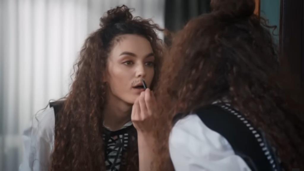 Nana domalowuje sobie wąsy przed lustrem.