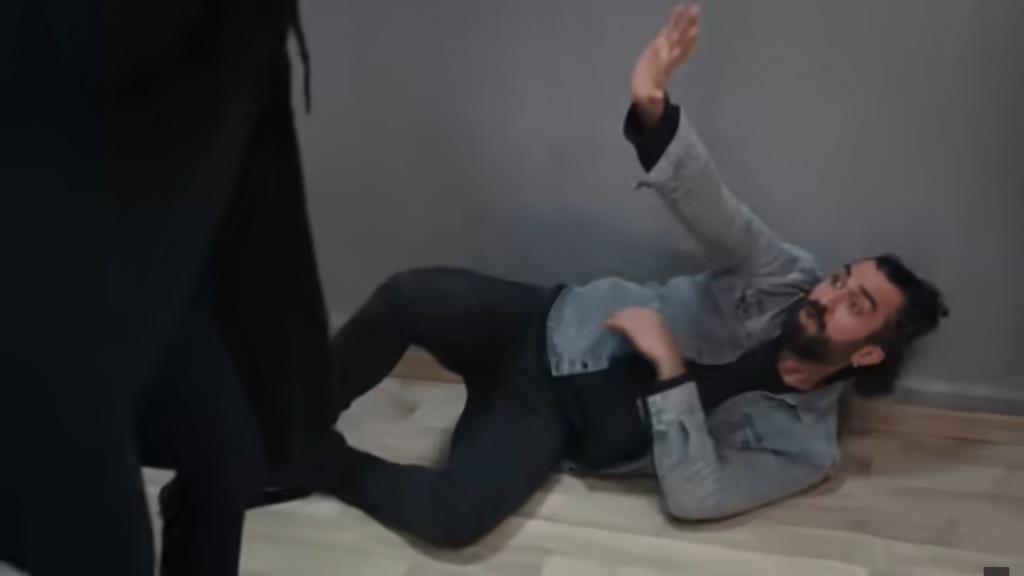 Ferit leży na podłodze, wyciągając przed siebie ręce w obronnym geście.