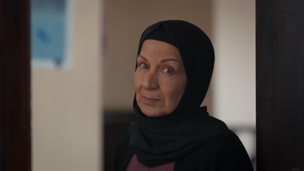 Akca stoi przy uchylonych drzwiach pokoju Nany.