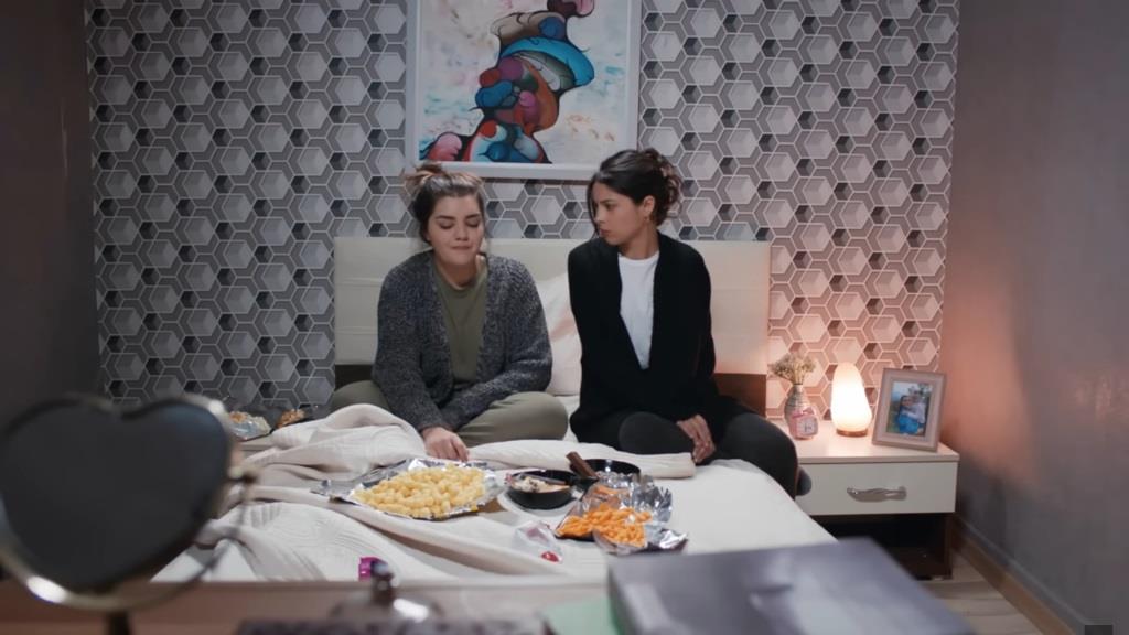 Nese i Ayse siedzą na łóżku.