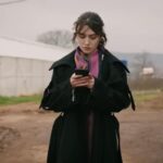 Zeynep znajduje się na polach uprawnych. W rękach trzyma telefon.