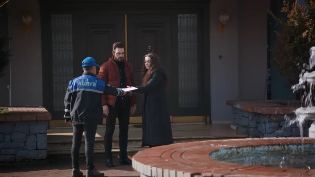 Scena przed rezydencją. Nana odbiera przesyłkę od kuriera. Obok niej stoi Yaman.