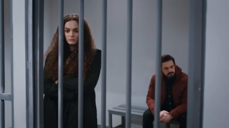 Kadr z serialu "Dziedzictwo". Yaman i Nana są zamknięci w jednej celi na komisariacie. Nana stoi przy kratach ze skrzyżowanymi rękami na klatce piersiowej, a Yaman siedzi na ławce.