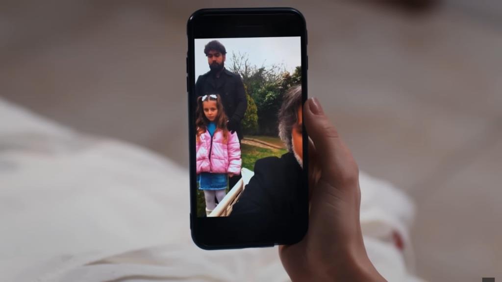 Zbliżenie na ekran telefonu Nany. Widać na nim część twarzy Sergo Nerceliego oraz małą dziewczynkę, trzymaną przez draba.