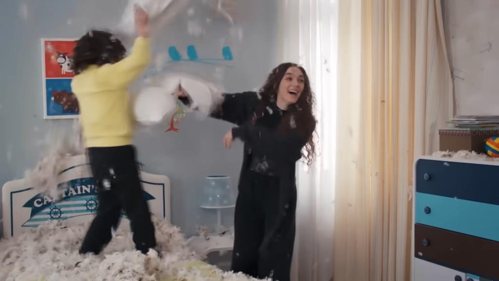 Yusuf i Nana toczą zaciętą bitwę na poduszki w pokoju chłopca. W powietrzu wirują puchowe pierza, tworząc magiczną atmosferę radości i beztroski.