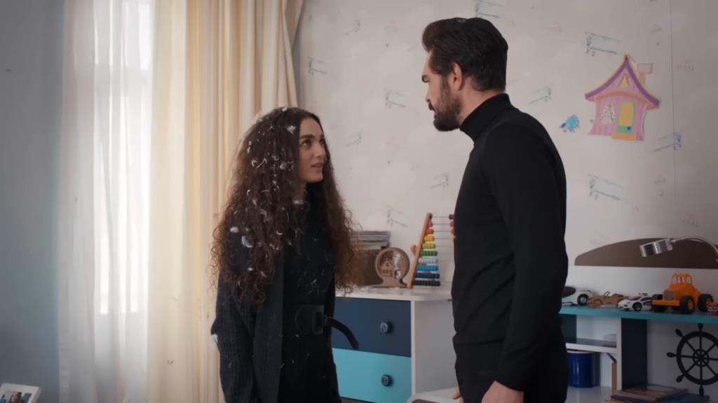 Yaman staje przed Naną, która pokryta jest pierzami z poduszek.