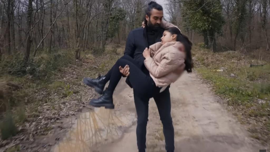 Ferit niesie Ayse na rękach drogą przez las.