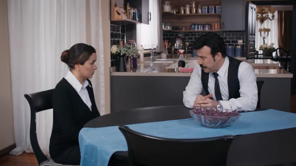 Cenger rozmawia z Aynur. Oboje siedzą przy stole w kuchni.