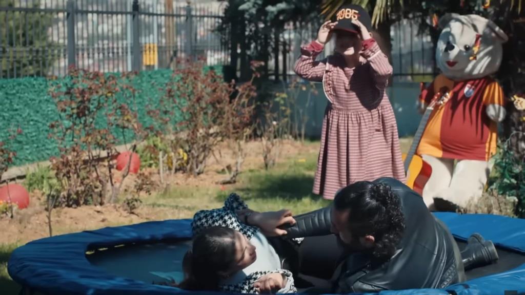 Ayse i Ferit przewrócili się na trampolinie. Doga poprawia sobie czapkę.