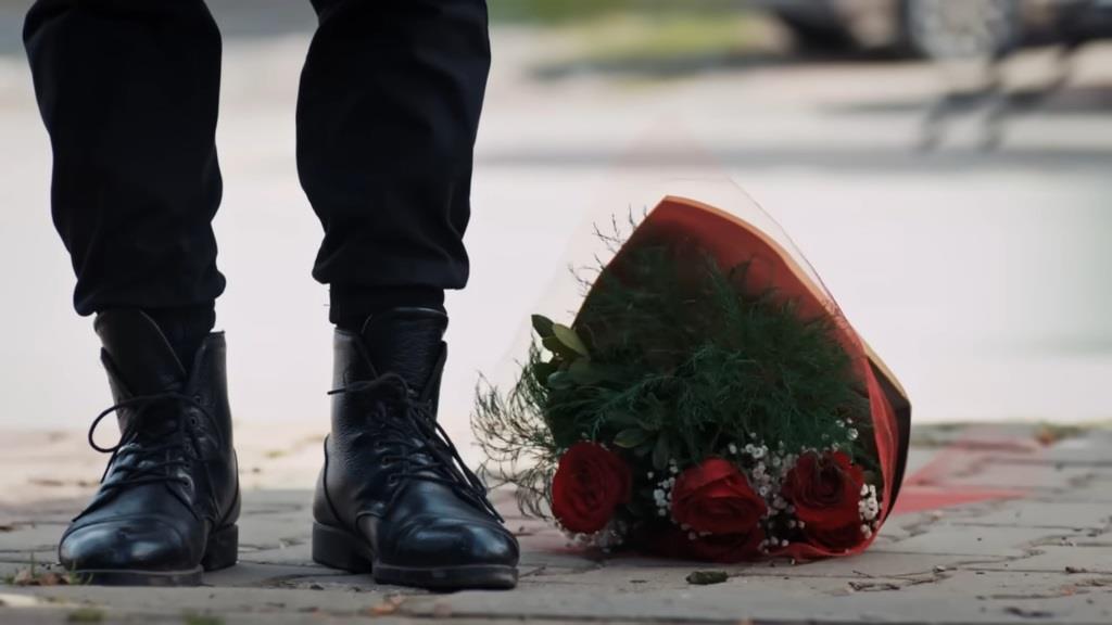 Zbliżenie na leżący na ziemi bukiet czerwonych róż, który Volkan upuścił.