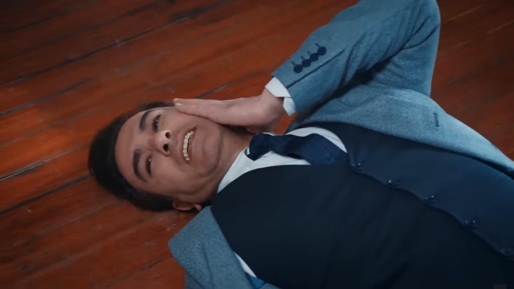 Nedim leży na podłodze i trzyma się za policzek.