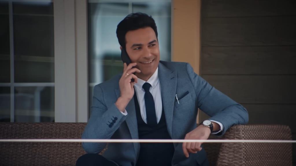 Nedim rozmawia przez telefon, śmiejąc się.