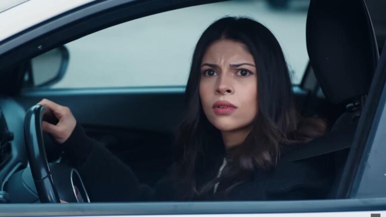 Ayse wygląda przez opuszczoną szybę.