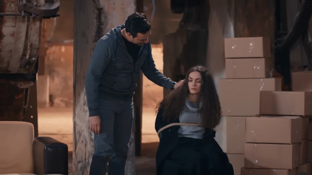 Nedim gładzi włosy przywiązanej do krzesła Nany.