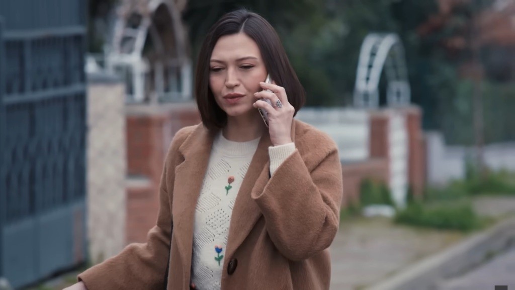 Akasya rozmawia przez telefon, stojąc na zewnątrz.