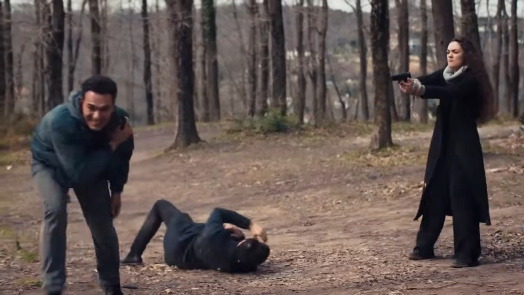 Nana trzyma pistolet w ręku, którym mierzy w kierunku uciekającego Nedima. Yaman leży na ziemi.