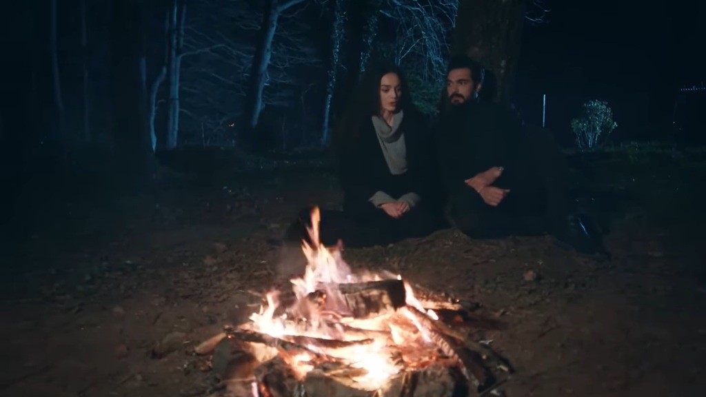 Yaman i Nana siedzą nad ogniskiem w lesie.