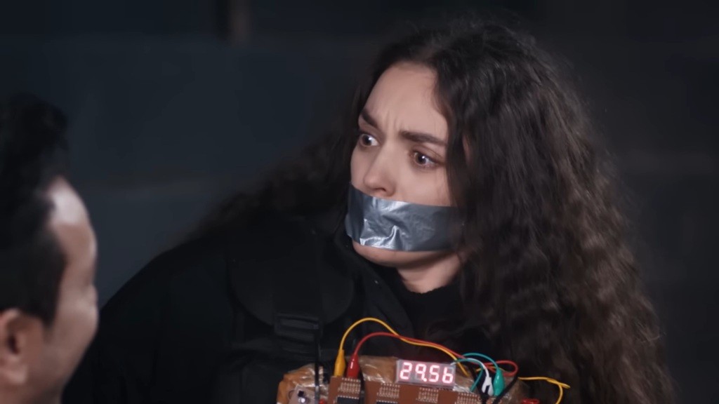 Nedim przytwierdza do ciała Nany atrapę bomby.