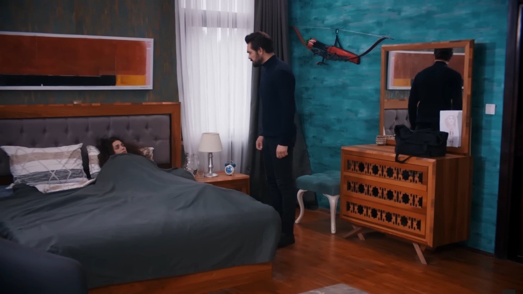 Yaman stoi nad łóżkiem, na którym leży Nana.