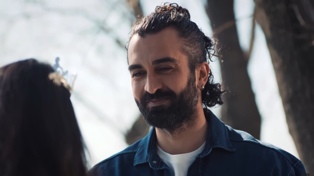 Ferit uśmiecha się, patrząc na Ayse.