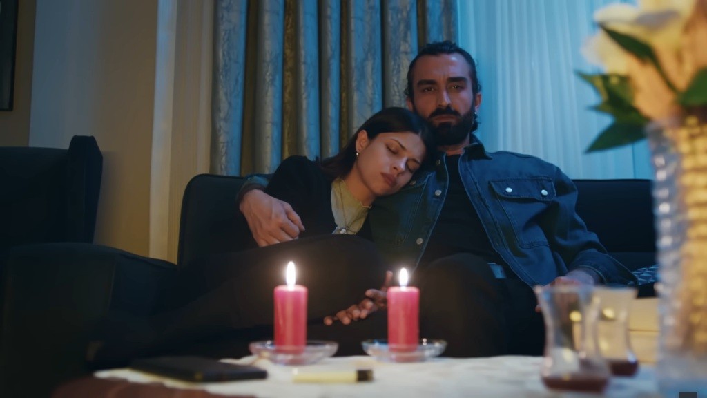 Ayse zasypia na ramieniu Ferita. Na stole stoją dwie płonące świece.