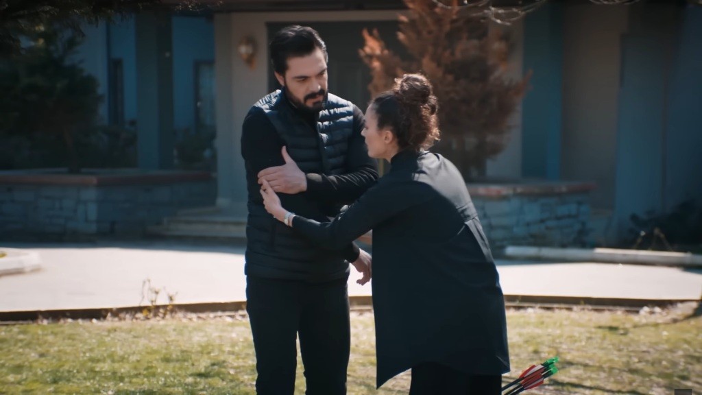 Yaman trzyma się za ramię, a Nana, wyraźnie przestraszona, ujmuje jego rękę.