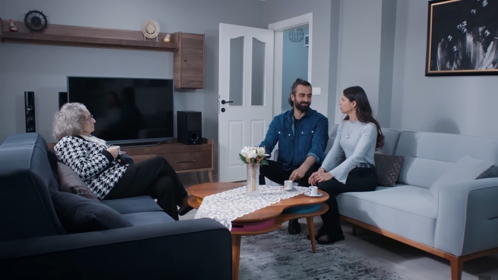 Scena w mieszkaniu, z którego Ayse i Ferit prowadzą obserwację. Naprzeciwko nich siedzi niezapowiedziany gość.