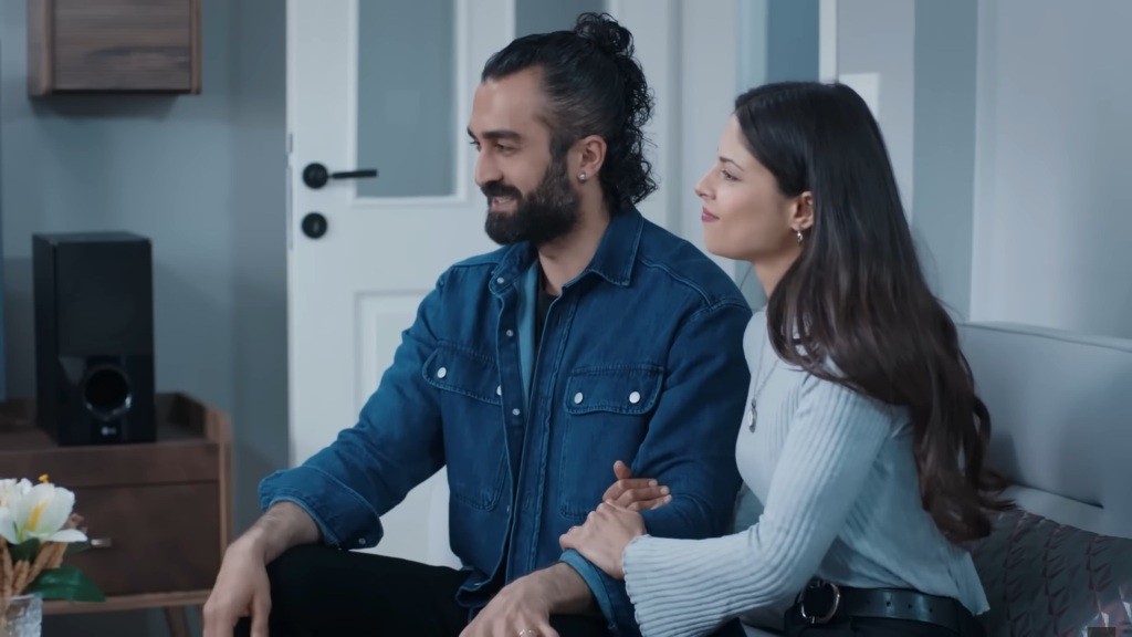 Ayse ujęła Ferita za ramię. Oboje są uśmiechnięci.