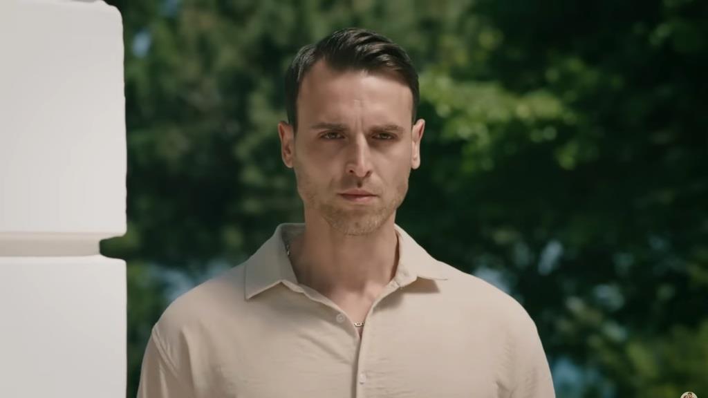 Alper stoi przy ścianie.